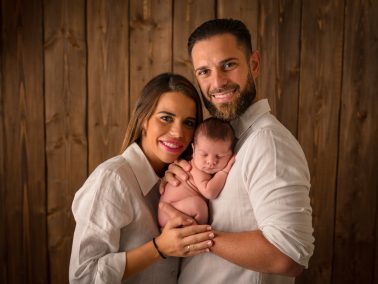 Padres abrazando a su bebé durante sesión newborn profesional en Alicante