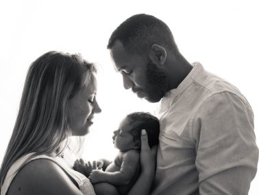 Hermanos junto a su bebé recién nacido en sesión newborn en Alicante