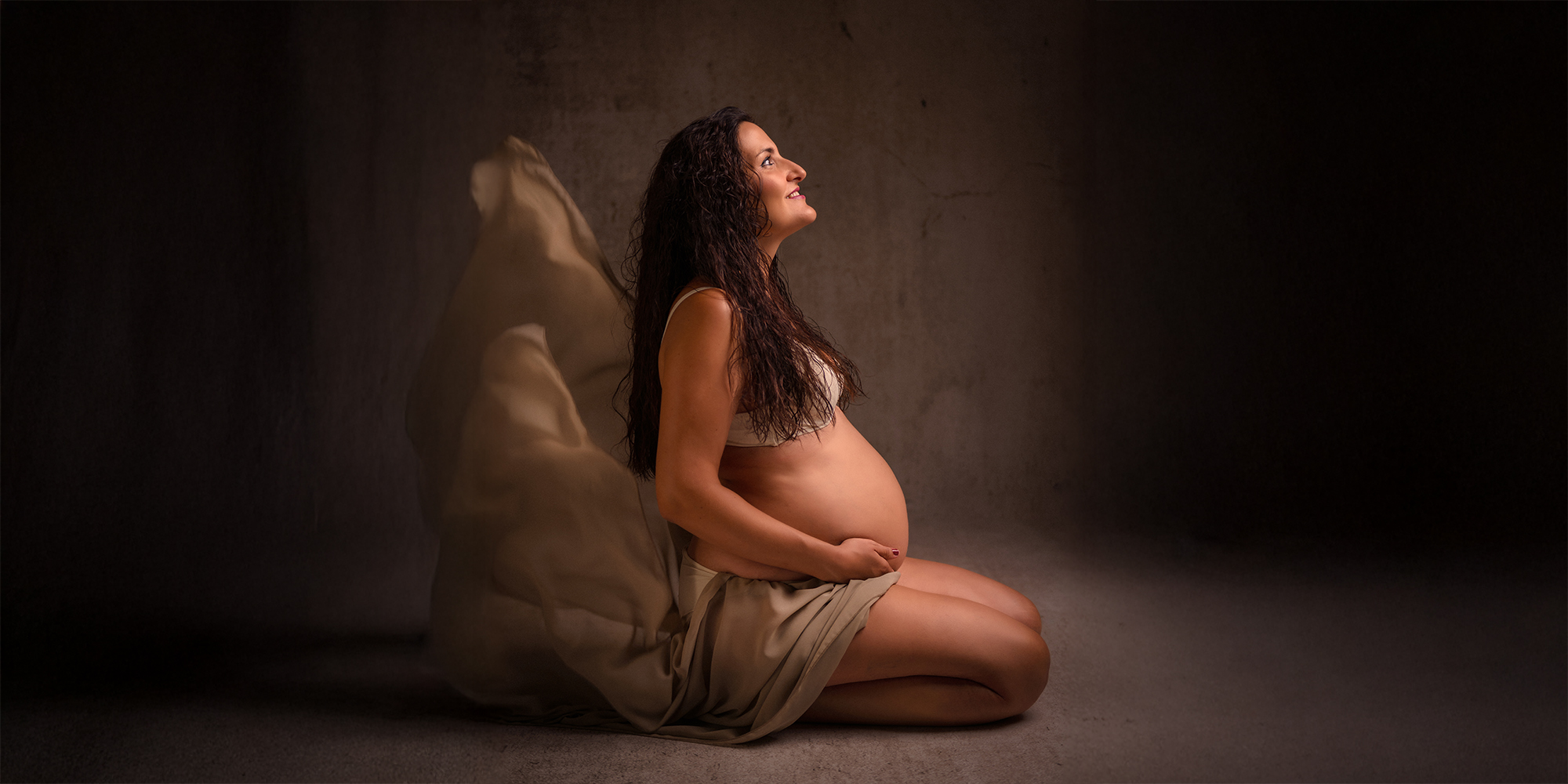 Sesión de fotos premamá en Alicante con luz natural y futura mamá acariciando su barriga